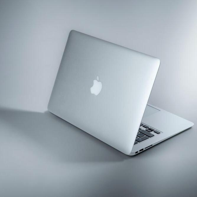 展示的是一台纯灰色背景的苹果电脑.